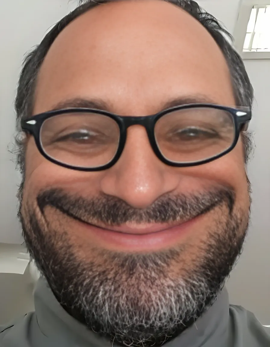 a man with a beard and glasses smiling