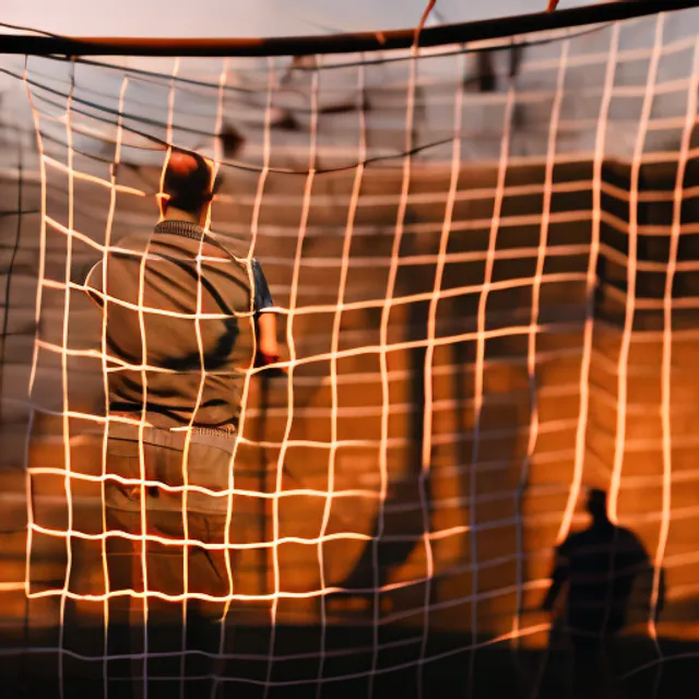 a person standing in front of a soccer goal with a crowd in the background

