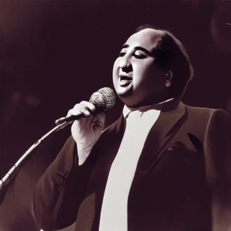 Mohammad Rafi singing on stage with a microphone in his hand