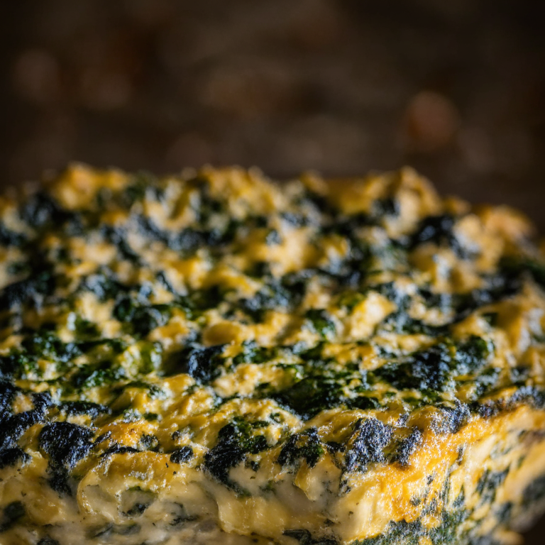 a close up photo of an Oven-Baked Frittata with Spinach and Cheese filling most of the frame, well lit with clear studio lighting and less than 2% blurry areas