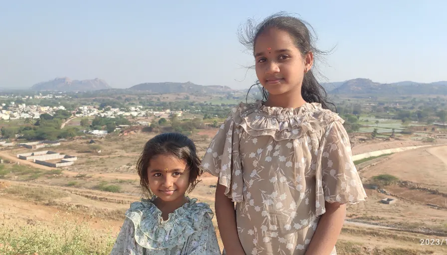 two young girls standing next to each other in a field