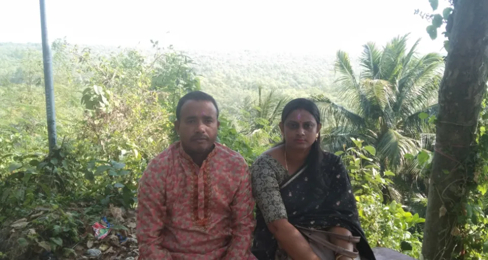 a man and woman sitting on a bench in the jungle