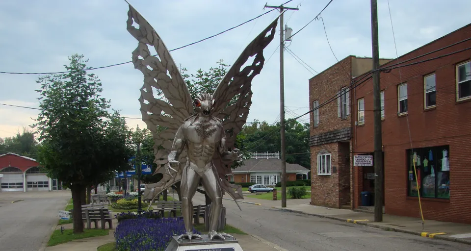 a statue of a man with wings on a city street