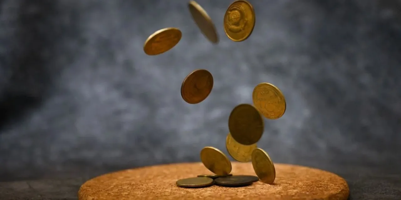 Coins falling on white background, shot from below