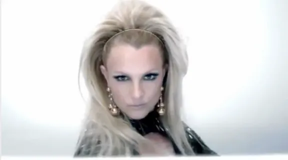 Highly detailed and hyper realistic Britney Spears in black outfit with beautiful intricate and detailed blonde hair blowing before her eyes, ultra detailed face and ultra realistic Smokey eyes and make-up, 8k octane render, cinematic, musicvideo, beauty shot, professional studio lighting, 