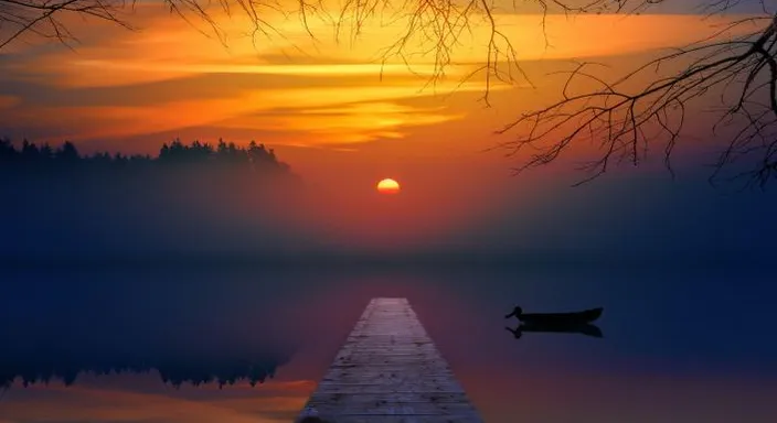 a boat floating on a lake at sunset