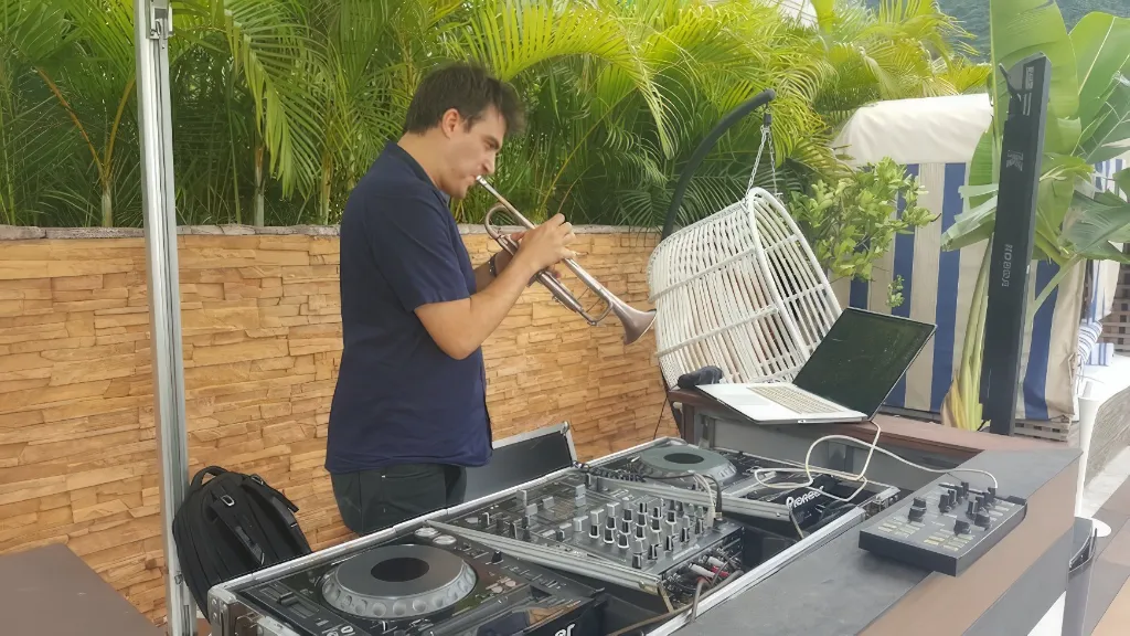 A man playing the pan flute in front of a dj booth. instead, a man playing the pan flute