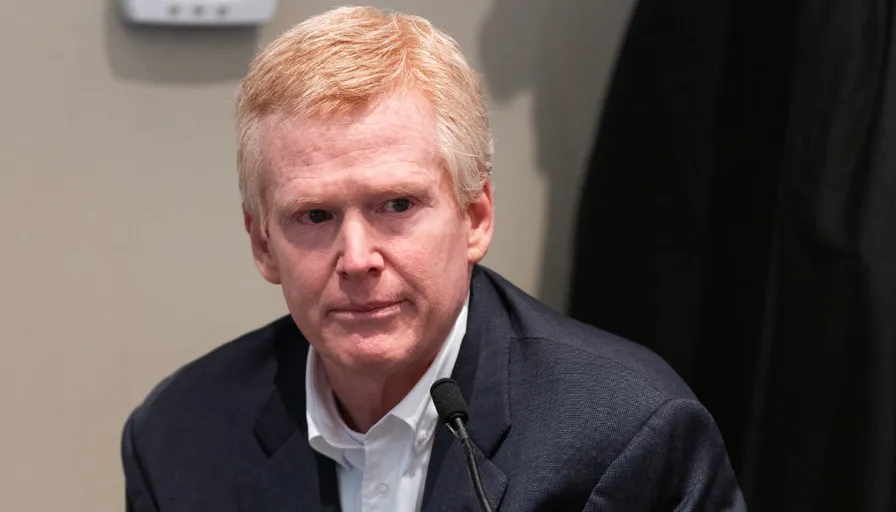 a man in a suit sitting in front of a microphone