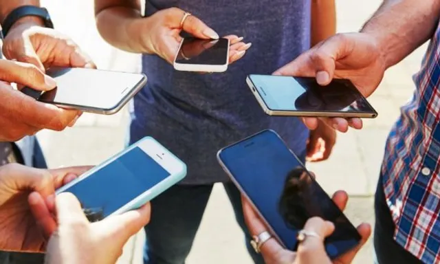 a group of people standing around each other holding cell phones