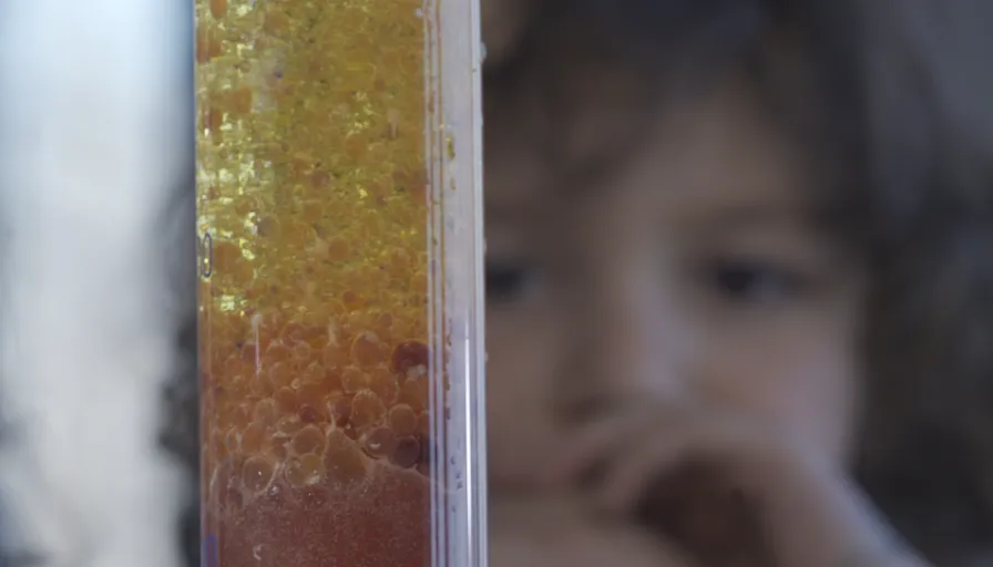 a child is looking through a tube of liquid
