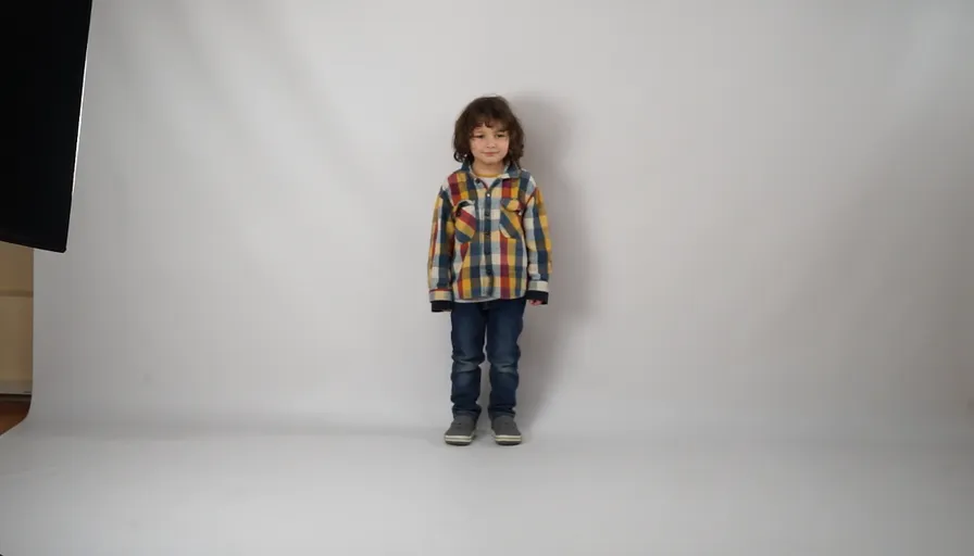 a young boy standing in front of a white background