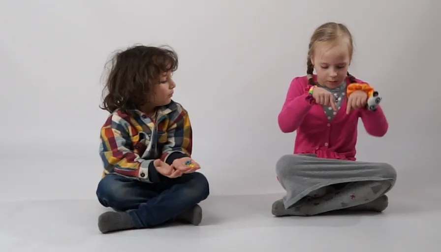 two little girls sitting on the ground playing with toys