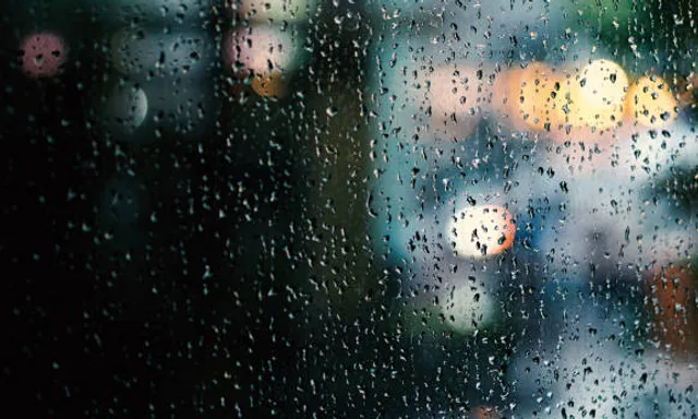 rain drops on a window with a blurry city street in the background