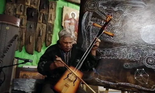 a man playing a guitar in front of a painting