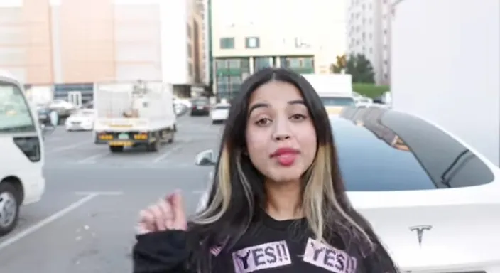 a woman making a funny face while standing in front of a car