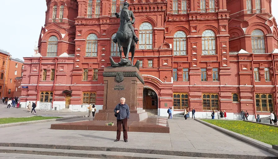 a man standing in front of a building with a statue of a man on a