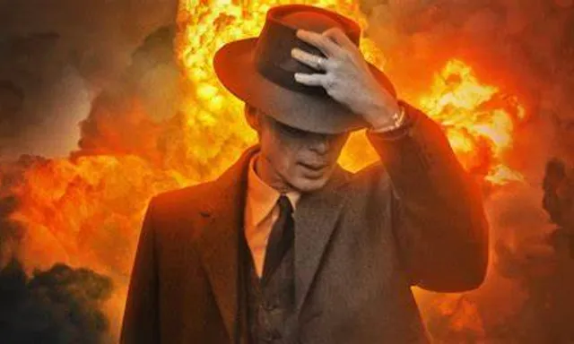 a man in a suit and hat standing in front of a fire