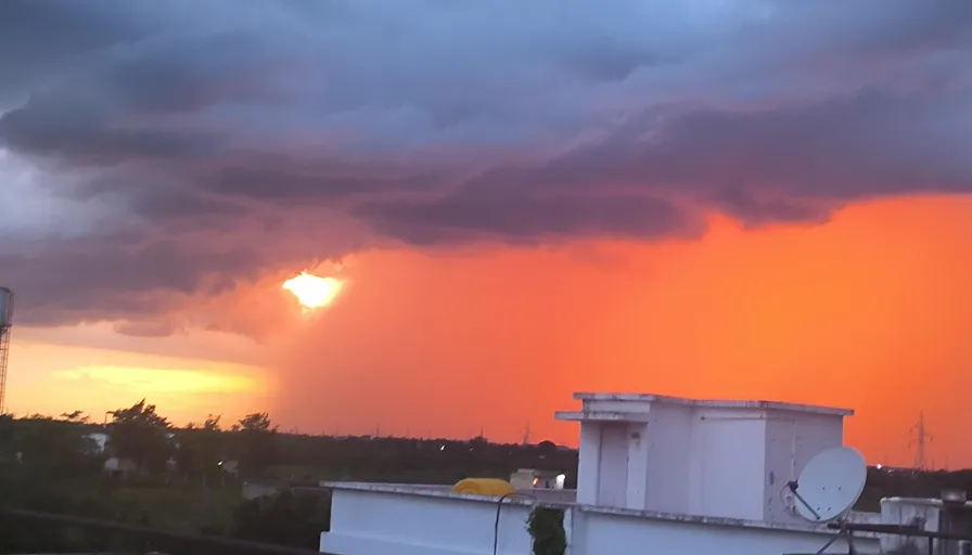 a large storm cloud looms over a city at sunset