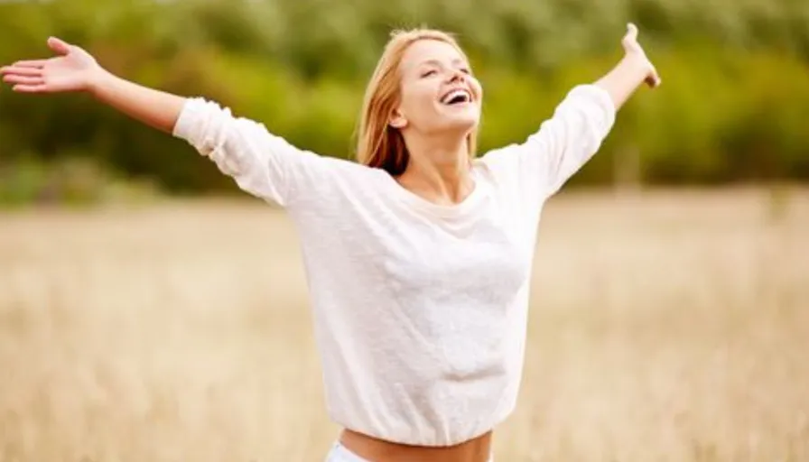 a woman standing in a field with her arms outstretched