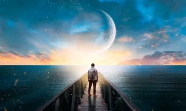 a man standing on a pier looking at the moon and ocean
