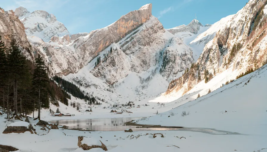 a winter scene with snow covered mountains and a lake