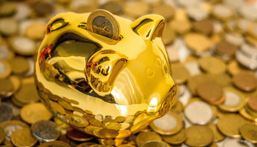 a golden piggy bank sitting on top of a pile of coins