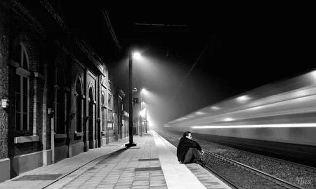 a man sitting on a train platform at night