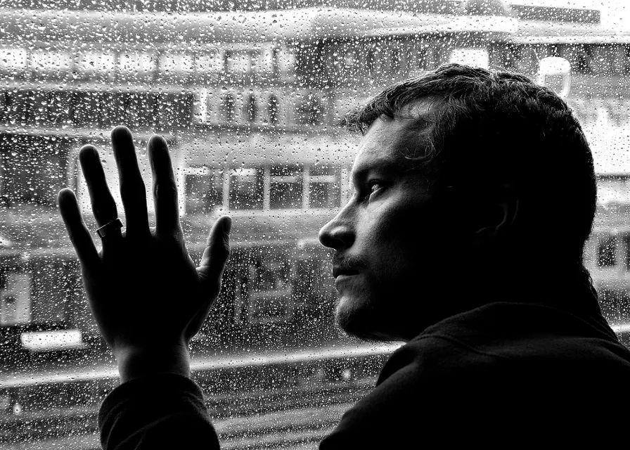 a man standing in front of a window with his hand up. black, human, temple, standing, black-and-white, gesture, style, flash photography, tints and shades, monochrome