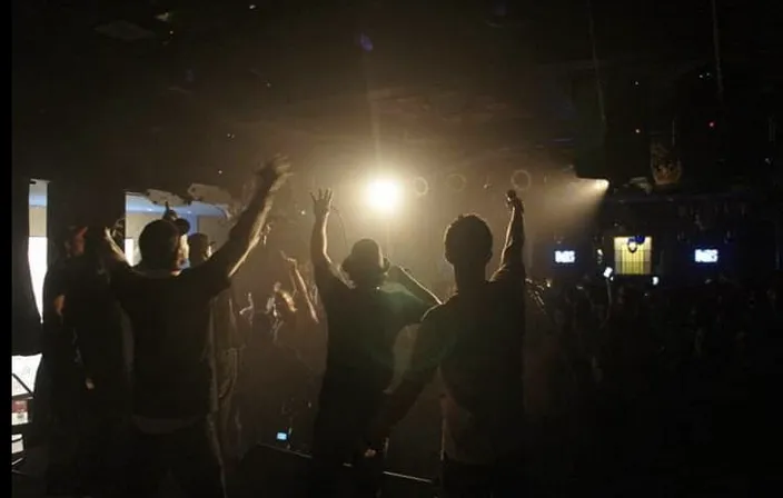 a group of people standing on top of a stage. concert, music, performing arts, entertainment, band plays, music artist, musician, music venue, stage, performance art