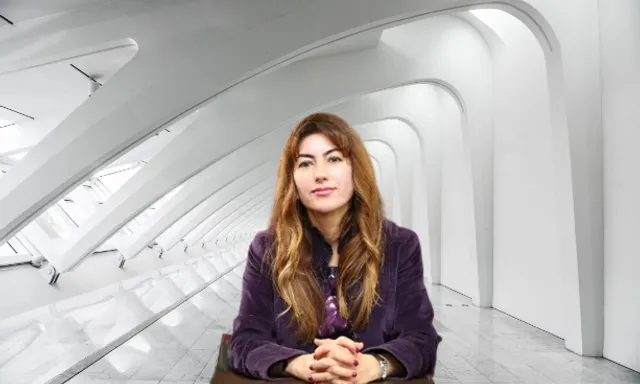 A woman takes in the view from her chair in a room. A woman sitting in a room with a view