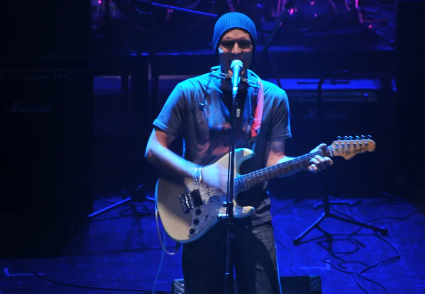 a man playing a guitar and singing into a microphone