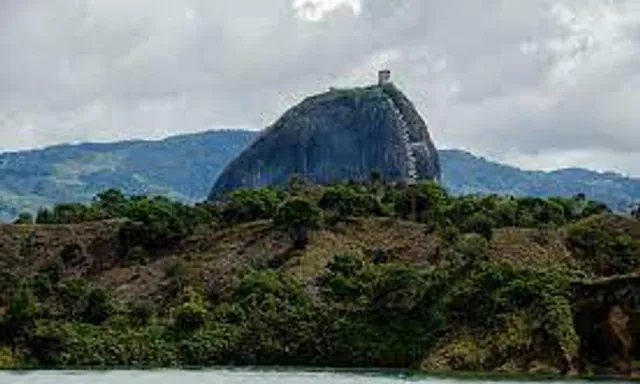 a large rock sitting on top of a lush green hillside