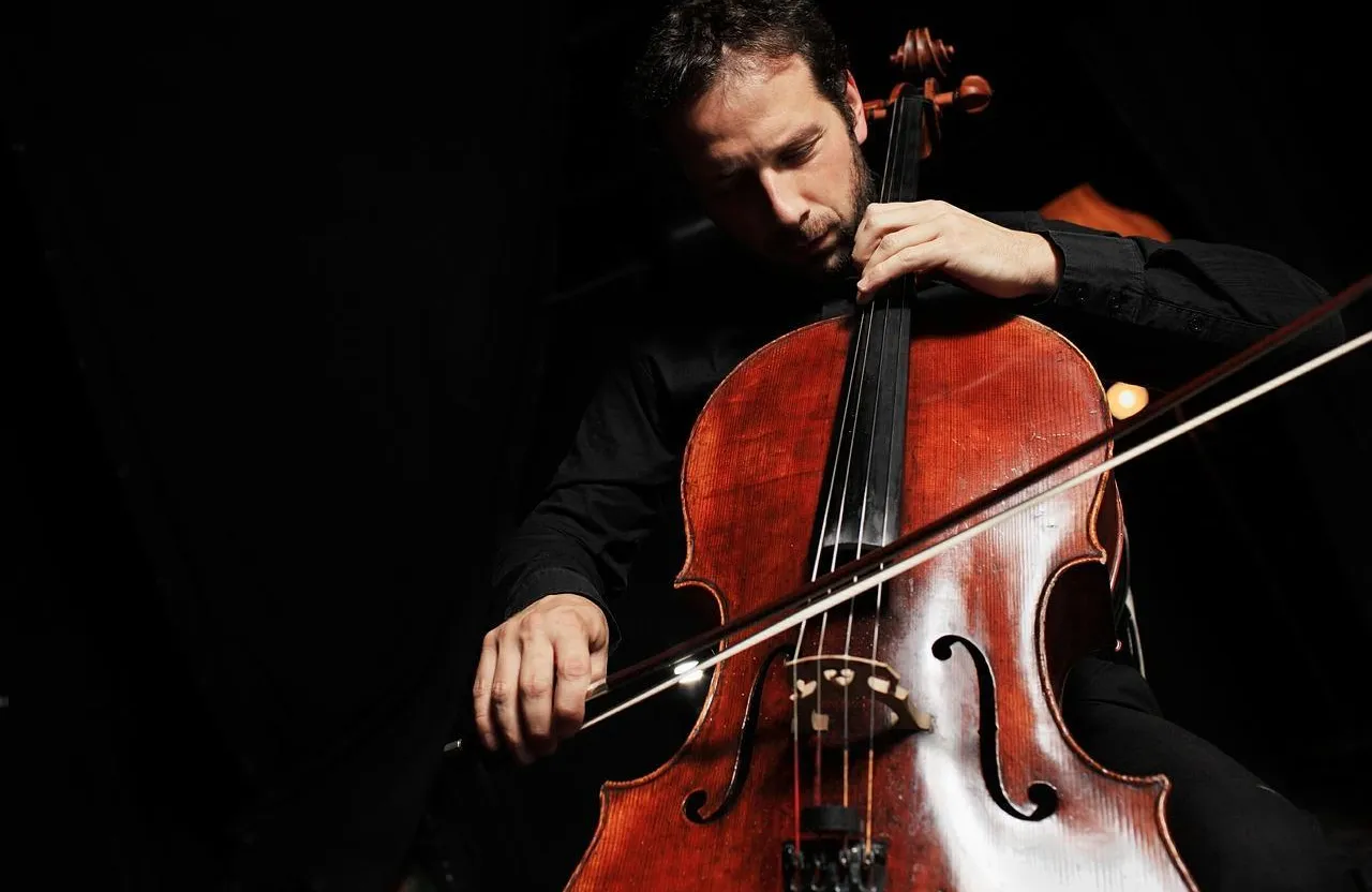 a man playing a cello in a dark room