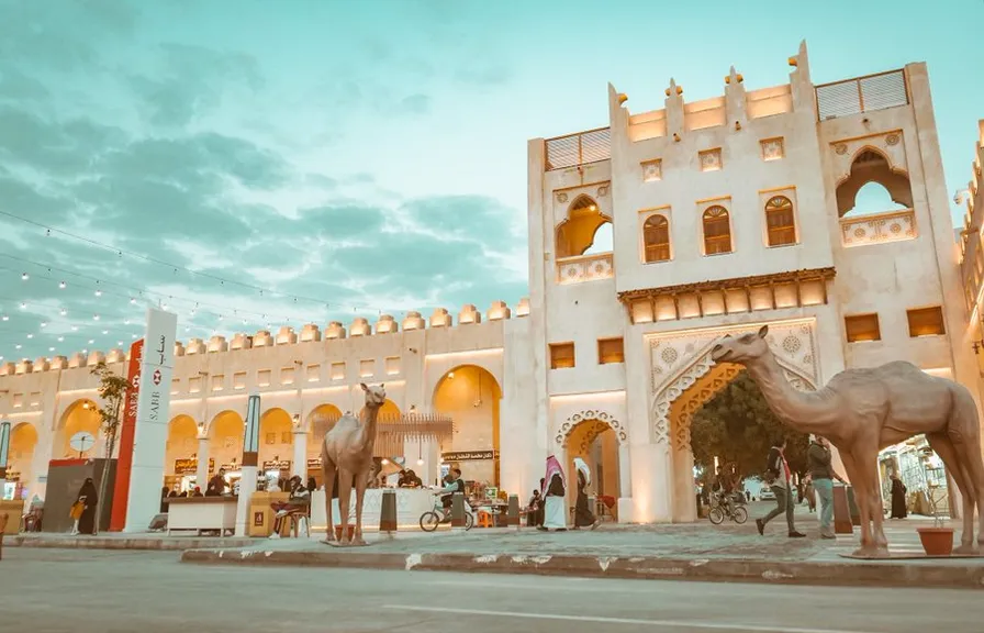 a large white building with a horse statue in front of it. sky, cloud, facade, landscape, building, art, city, arcade, arch, leisure