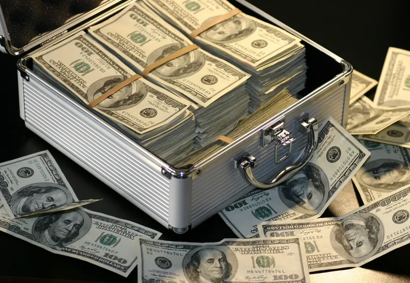 A Briefcase Full of Money Sitting on Top of a Table of Coins (Foto: Antoine Van Agtmael). gold money with coins