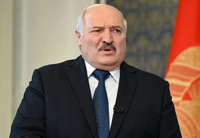 a man in a suit and tie standing in front of two flags