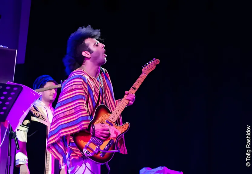 a man standing on a stage with a guitar