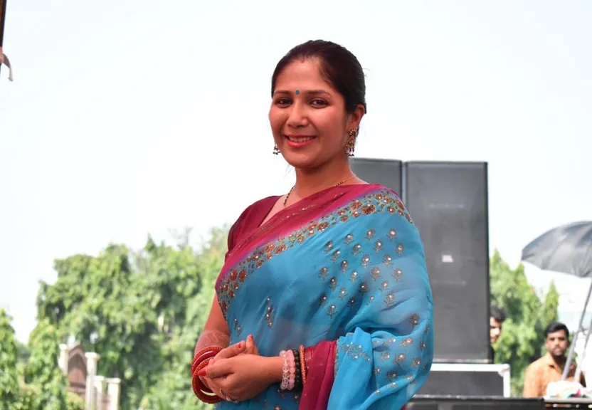 a woman in a blue sari standing in front of a stage