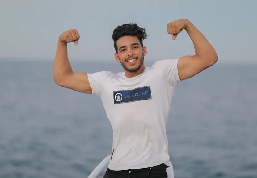 a man flexing his muscles on the beach. Change the man to superman