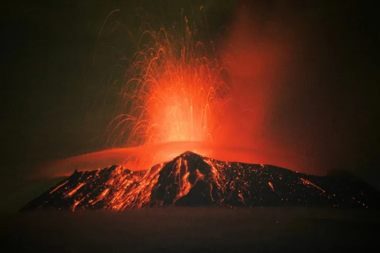 a volcano erupts lava as it erupts into the night sky