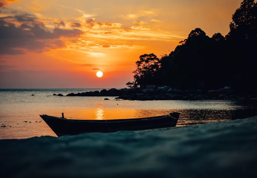 a boat sitting on top of a beach near the ocean