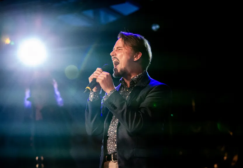 a man singing into a microphone in front of a crowd