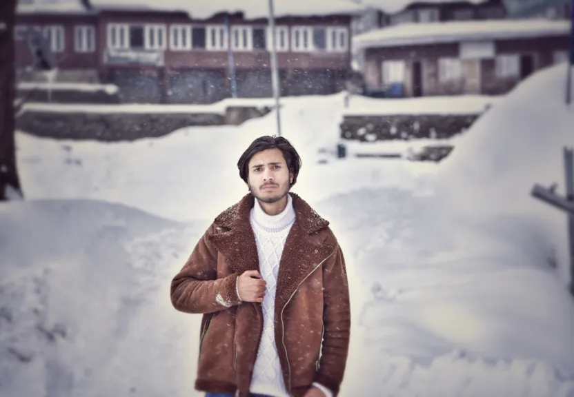 a man standing in the snow in front of a building nake snow more and in background add some mountain and make him a body builder