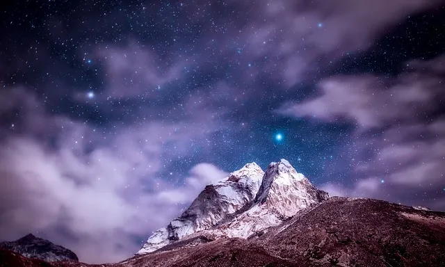 the night sky with stars above a mountain