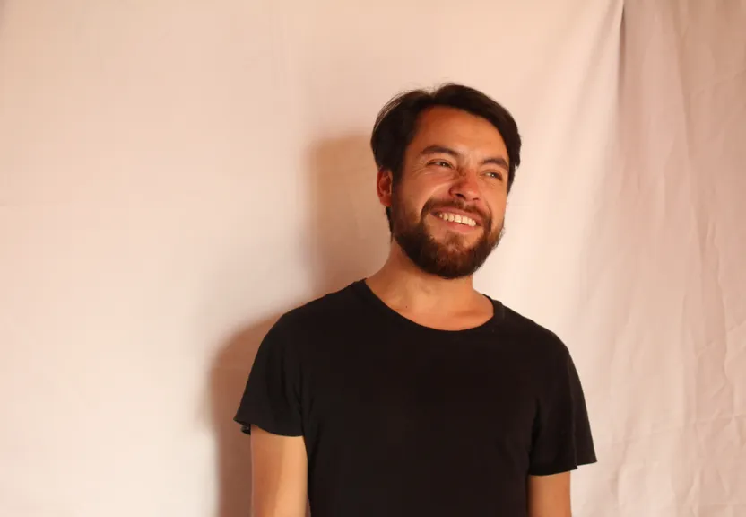 a man with a beard standing in front of a white backdrop