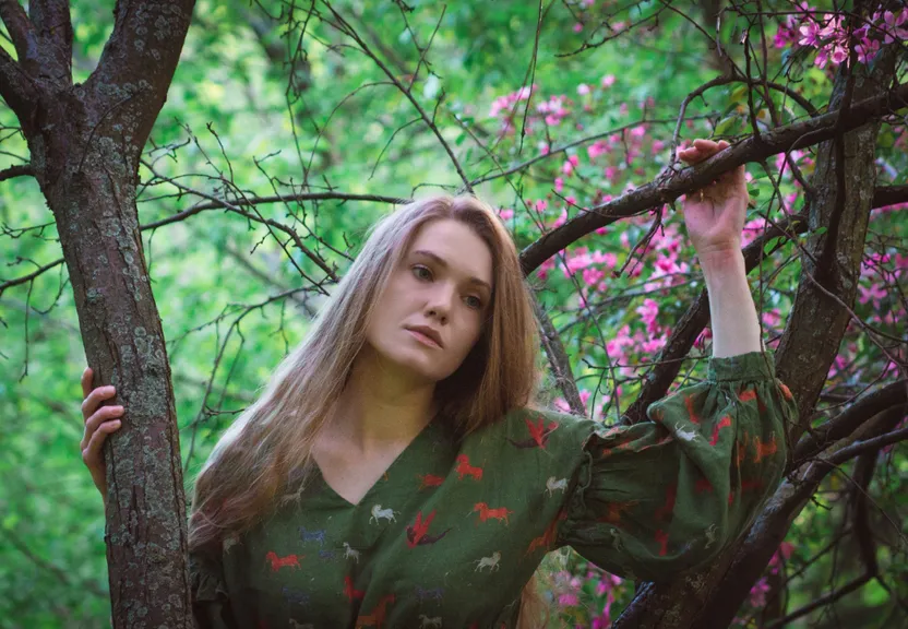a woman in a green dress standing in a tree