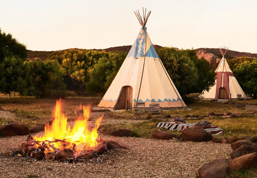 a teepee sitting next to a fire in a field