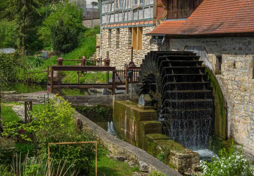 an old mill with a water wheel in the foreground