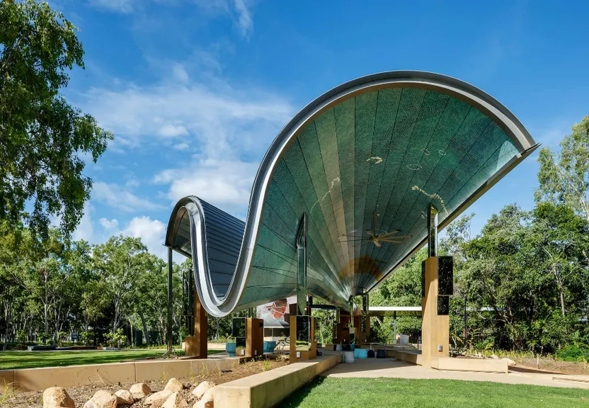 a large metal structure sitting on top of a lush green field