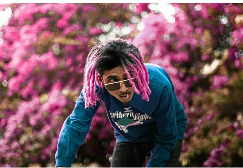 a man with pink dreadlocks and a blue shirt